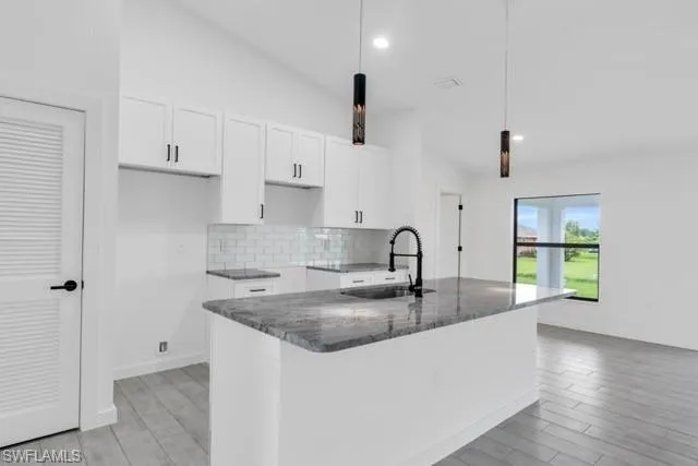 Kitchen island featuring a dark granite countertop and integrated sink with a matte black pull-down faucet