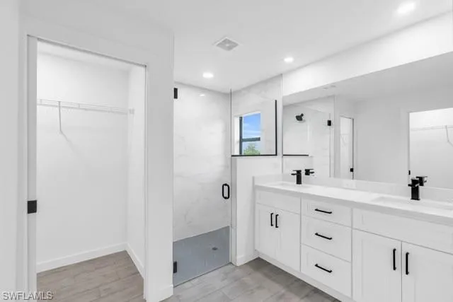 Modern bathroom featuring a dual vanity with white cabinetry and black hardware