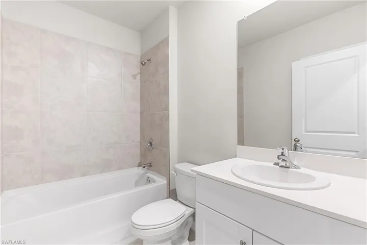 Full bathroom with vanity, tiled shower / bath combo, and toilet