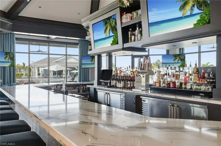 Community bar area with plenty of natural light, light stone counters, and open shelves
