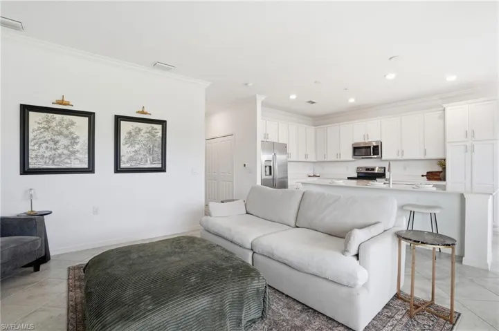 Living room featuring light tile patterned floors, ornamental molding, and recessed lighting