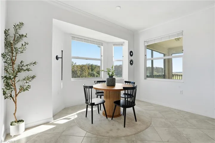 Dining area with ornamental molding, plenty of natural light, and light tile patterned flooring