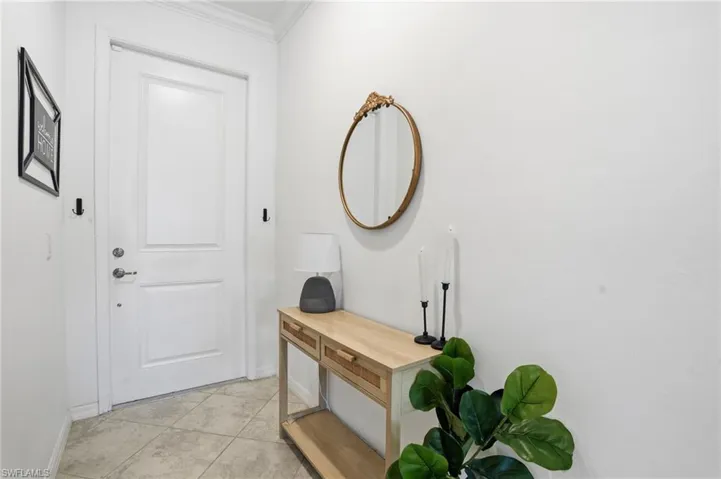 Foyer entrance with crown molding and light tile patterned flooring