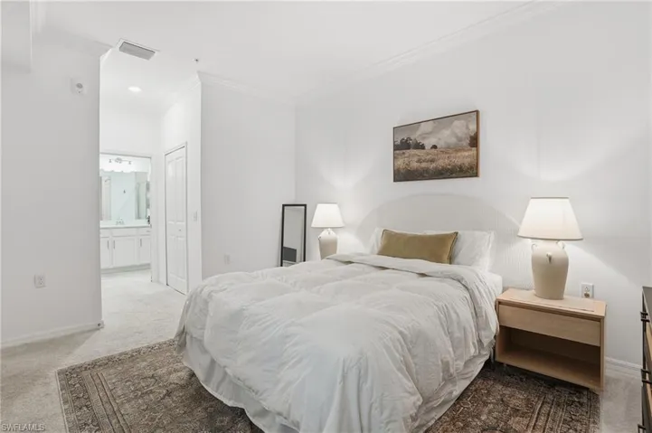 Carpeted bedroom featuring crown molding, a closet, and ensuite bath
