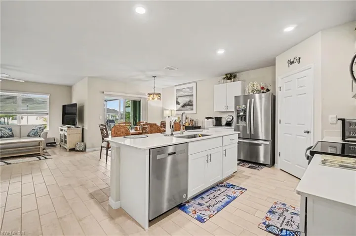 Kitchen with stainless steel appliances, pendant lighting, wood tiled floors, and white cabinets