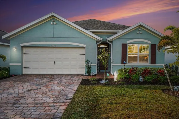 Ranch-style home featuring stucco siding, an attached garage, decorative driveway, and a lawn