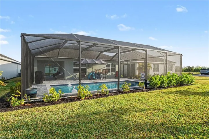 Back of house with a sunroom, an outdoor pool, a patio area, a lanai, and a yard