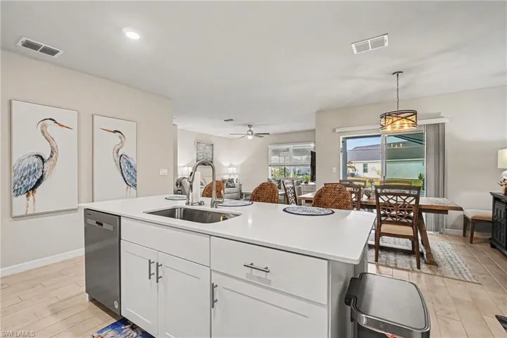 Kitchen featuring pendant lighting, white cabinetry, open floor plan, a kitchen island with sink, and light wood-style flooring