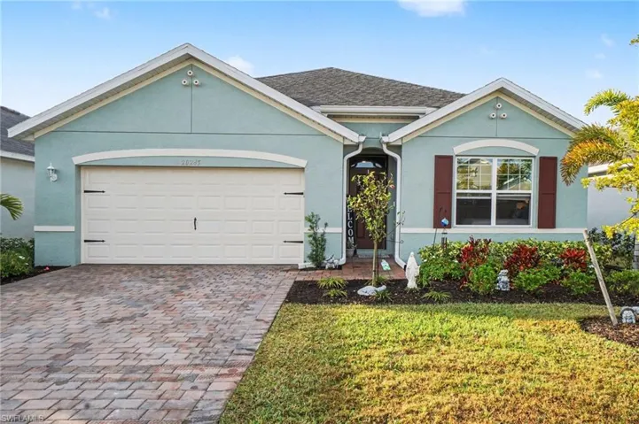 Ranch-style home featuring an attached garage, decorative driveway, stucco siding, and a front lawn