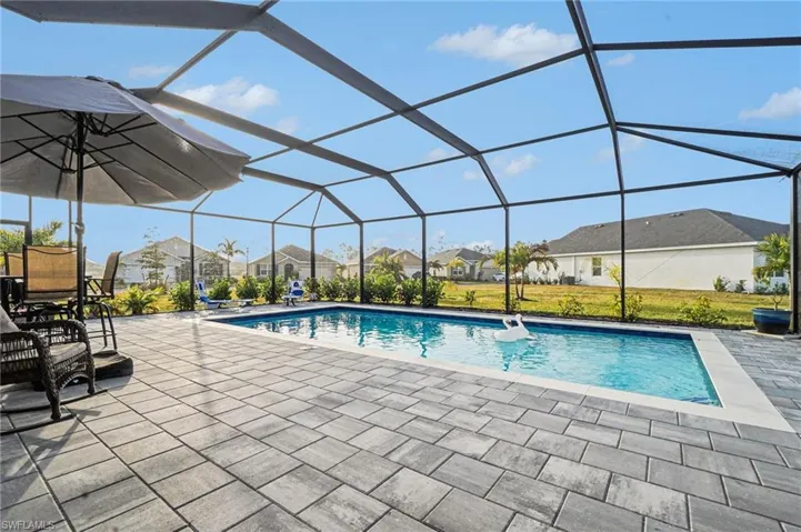 Swimming pool with a sunroom, a residential view, a lanai, a patio, and a lawn