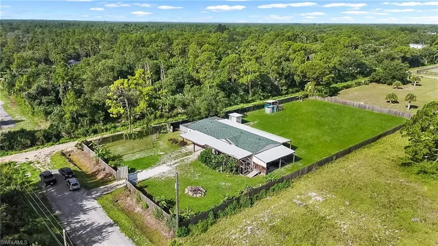 Expansive rural property featuring a modern metal-roofed barn structure with open grounds, mature tree-lined perimeter, and extensive manicured lawn acreage
