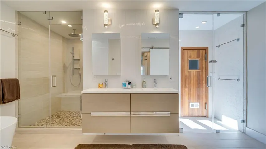 Bathroom with a shower stall, double vanity, recessed lighting, and a soaking tub