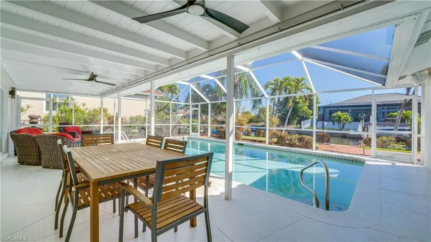 Outdoor pool with a sunroom, a patio, glass enclosure, and outdoor dining area