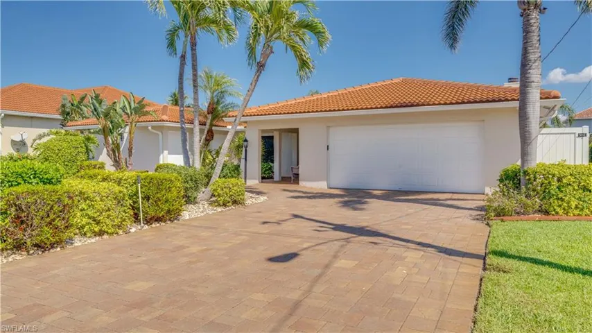 Mediterranean / spanish home with stucco siding, a tile roof, decorative driveway, and an attached garage