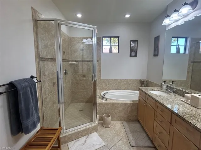Master Bathroom featuring separated tub and shower, vanity, walking closet and recessed lighting