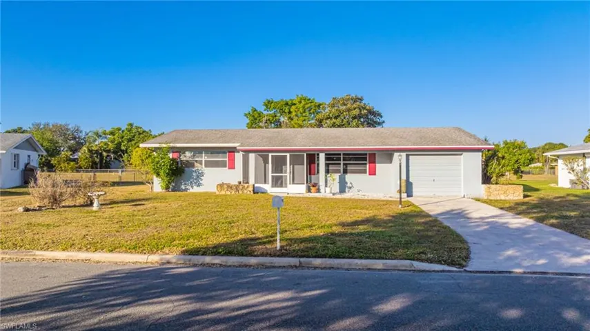Ranch-style house featuring a front lawn, concrete driveway, an attached garage, and stucco siding