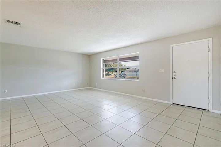 Empty room with a textured ceiling and light tile patterned floors