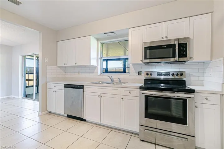 Kitchen with stainless steel appliances, plenty of natural light, white cabinets, and light countertops