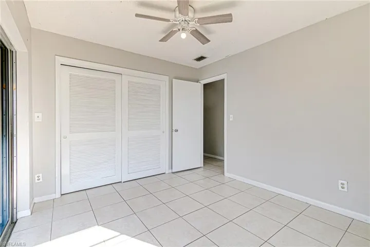 Unfurnished bedroom featuring ceiling fan, light tile patterned floors, and a closet