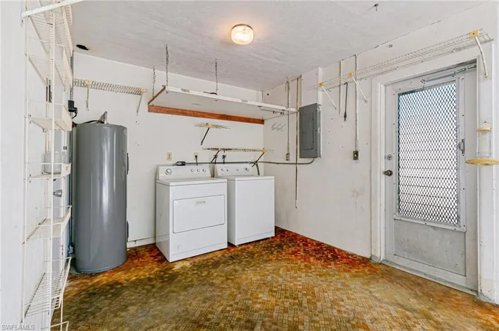 Laundry area featuring water heater, washer and dryer, electric panel, and a textured ceiling