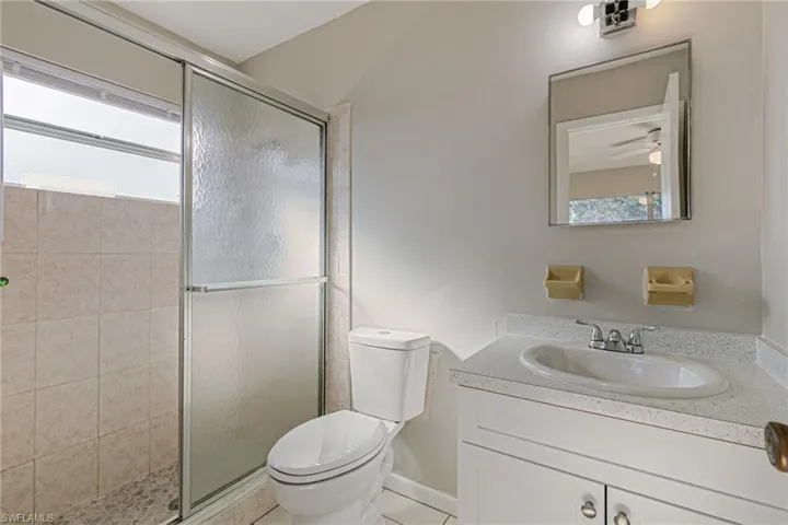 Full bath with vanity, a stall shower, and light tile patterned flooring