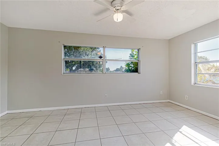 Unfurnished room with a textured ceiling, a ceiling fan, healthy amount of natural light, and light tile patterned flooring