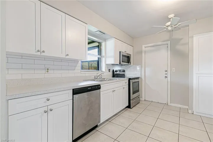 Kitchen featuring stainless steel appliances, white cabinets, a ceiling fan, light countertops, and tasteful backsplash