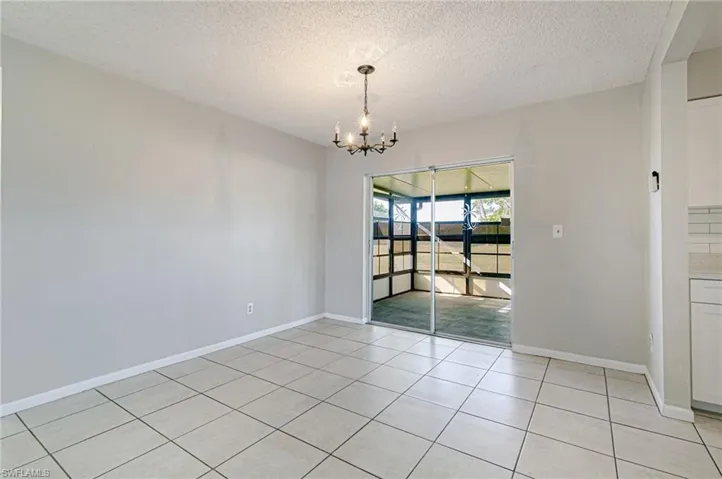Unfurnished dining area with hanging lights, a textured ceiling, and light tile patterned flooring
