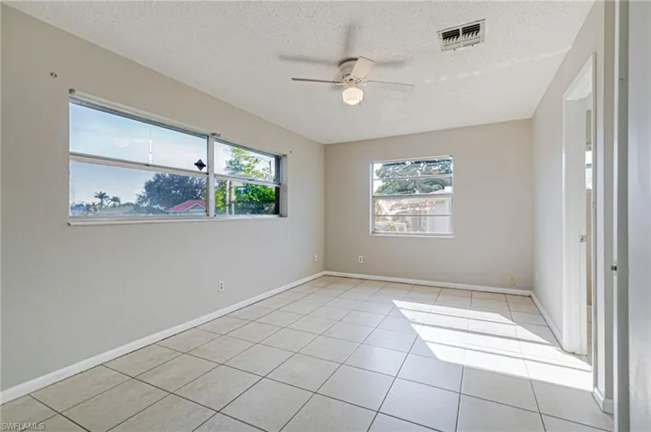 Spare room featuring a ceiling fan, light tile patterned flooring, and a textured ceiling