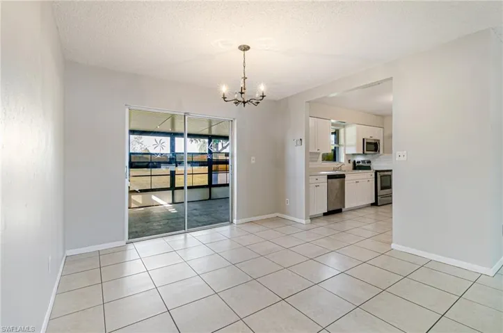 Unfurnished dining area with a textured ceiling, a chandelier, and light tile patterned flooring