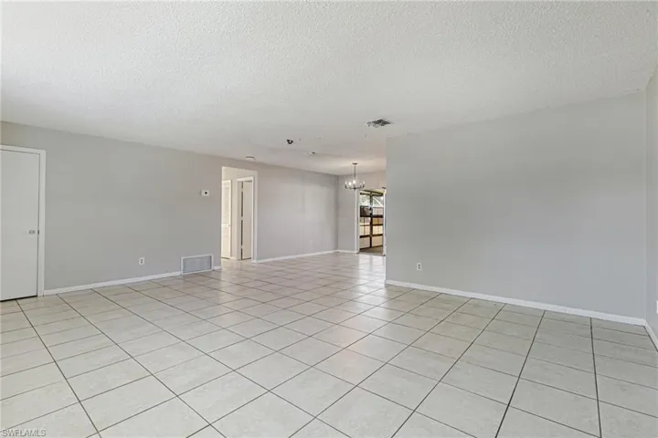 Spare room with a textured ceiling, light tile patterned flooring, and hanging lights