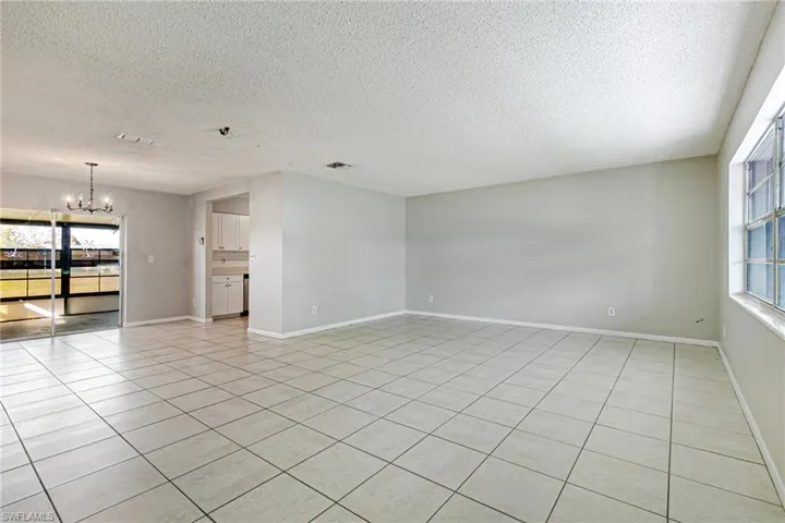 Spare room with a chandelier, a textured ceiling, and light tile patterned floors