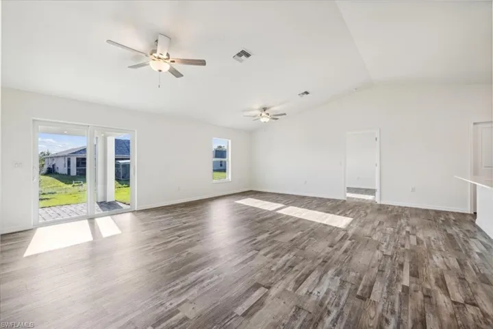 Unfurnished room with ceiling fan, vaulted ceiling, and wood-type flooring
