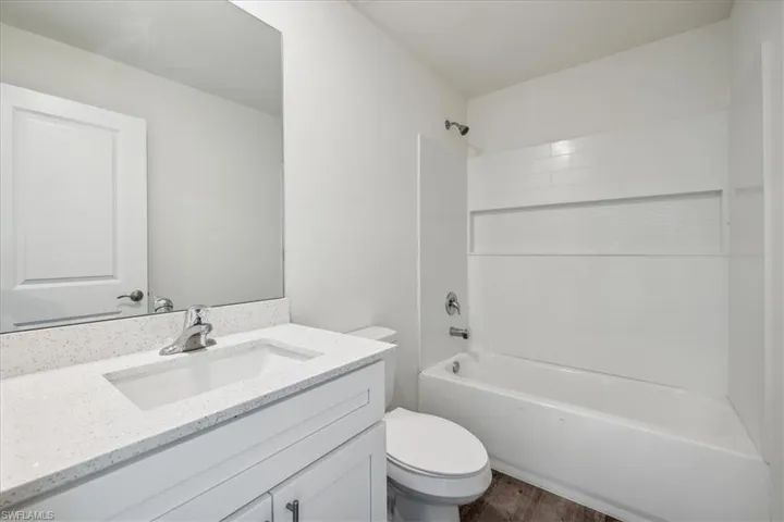 Full bathroom with shower / bath combination, hardwood / wood-style floors, toilet, and vanity