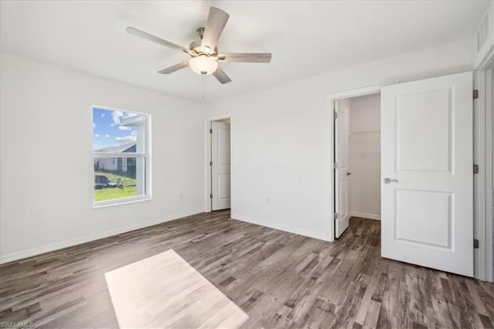Unfurnished bedroom featuring wood-type flooring, ceiling fan, a closet, and a spacious closet