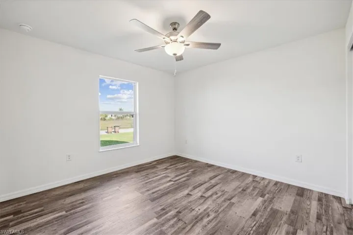 Empty room with ceiling fan and hardwood / wood-style flooring