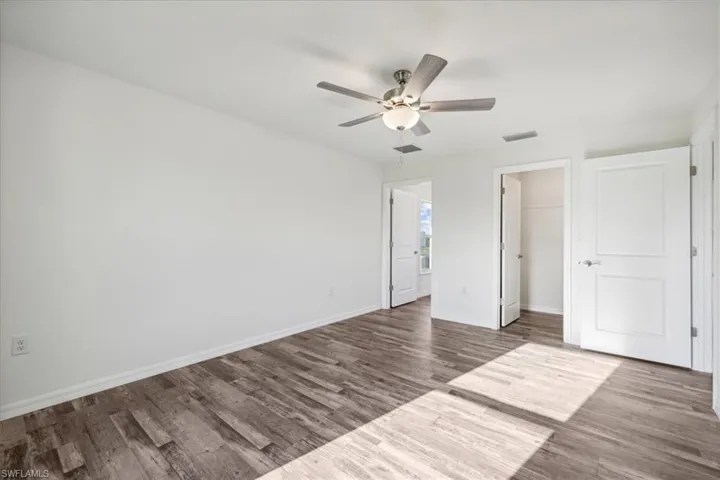 Unfurnished bedroom with a spacious closet, ceiling fan, a closet, and wood-type flooring