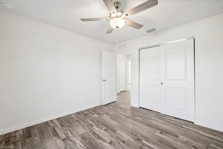 Unfurnished bedroom featuring a closet, wood-type flooring, and ceiling fan