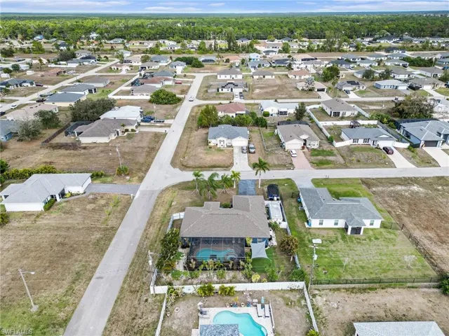 Aerial view of property and surrounding area featuring a pool and nearby suburban area