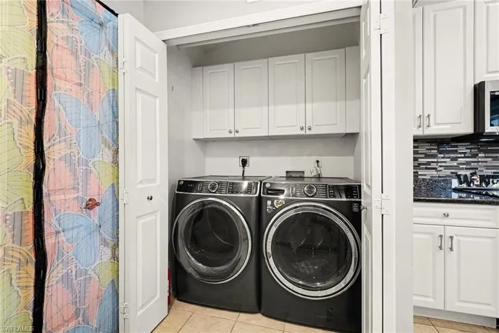 Laundry room with independent washer and dryer and light tile patterned floors