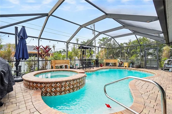 View of pool with glass enclosure, a pool with connected hot tub, a patio, and a sunroom