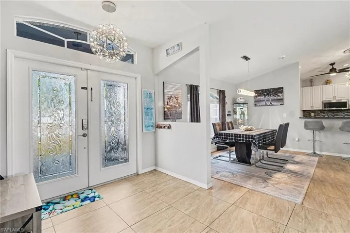 Foyer with a chandelier, lofted ceiling, french doors, a ceiling fan, and light tile patterned floors