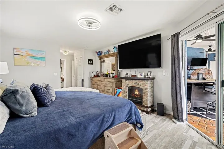 Bedroom with wood finished floors and a stone fireplace