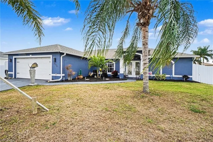 Ranch-style home featuring an attached garage, stucco siding, driveway, and french doors