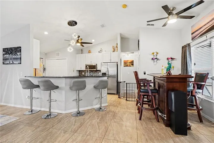Kitchen with a ceiling fan, a kitchen bar, stainless steel appliances, a peninsula, and backsplash