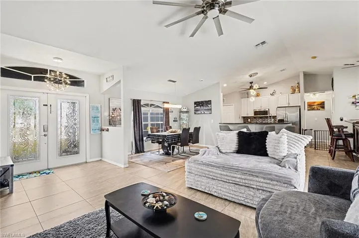 Living area featuring lofted ceiling, light tile patterned floors, and french doors