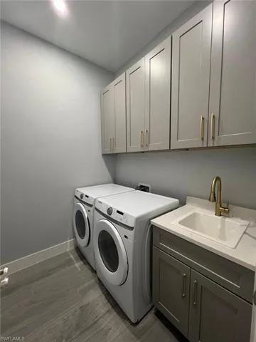 Laundry area featuring independent washer and dryer, cabinet space, and recessed lighting
