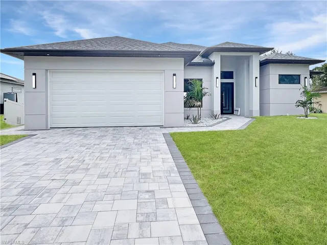 Prairie-style home featuring a front yard, stucco siding, driveway, and roof with shingles