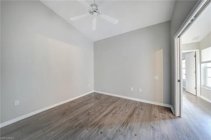 Unfurnished room with wood-type flooring, ceiling fan, and vaulted ceiling