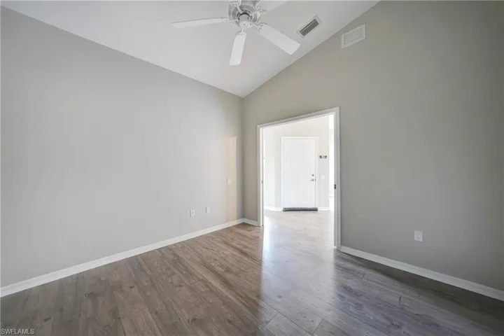 Unfurnished room featuring high vaulted ceiling, ceiling fan, and dark hardwood / wood-style flooring